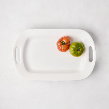 White ceramic handled serving platter with two heirloom tomatoes.
