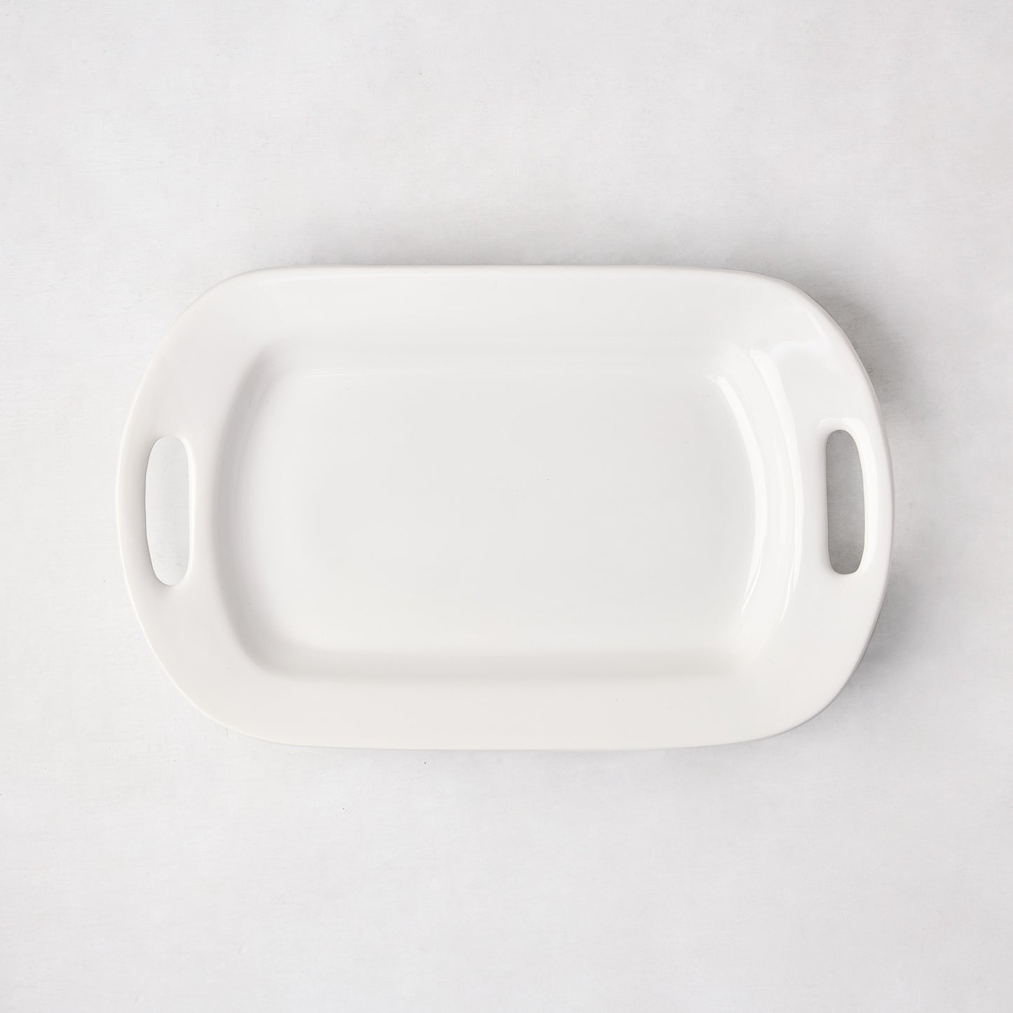 White ceramic small handled serving platter, 15"L x 9"W, with elegant handles.