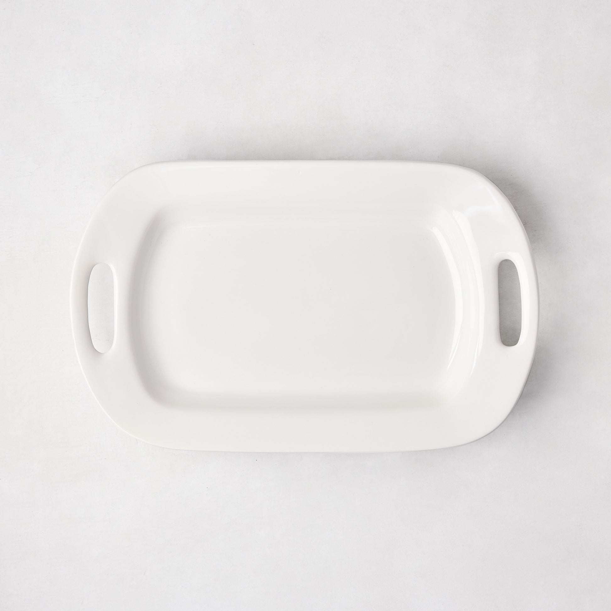 White ceramic small handled serving platter, 15"L x 9"W, with elegant handles.