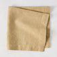 Chai HG Signature hand-dyed linen napkin, 22-inch square, creamy nutmeg color, folded.