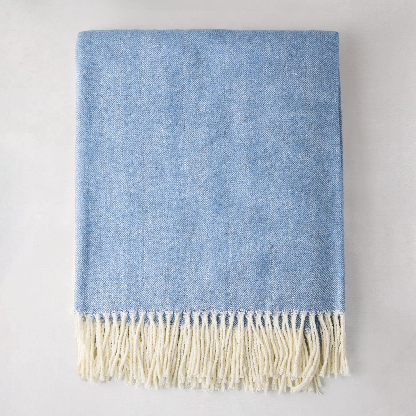 Chambray blue Italian herringbone throw blanket with cream fringe, 51"W x 67"L, 50% cotton, 50% acrylic.