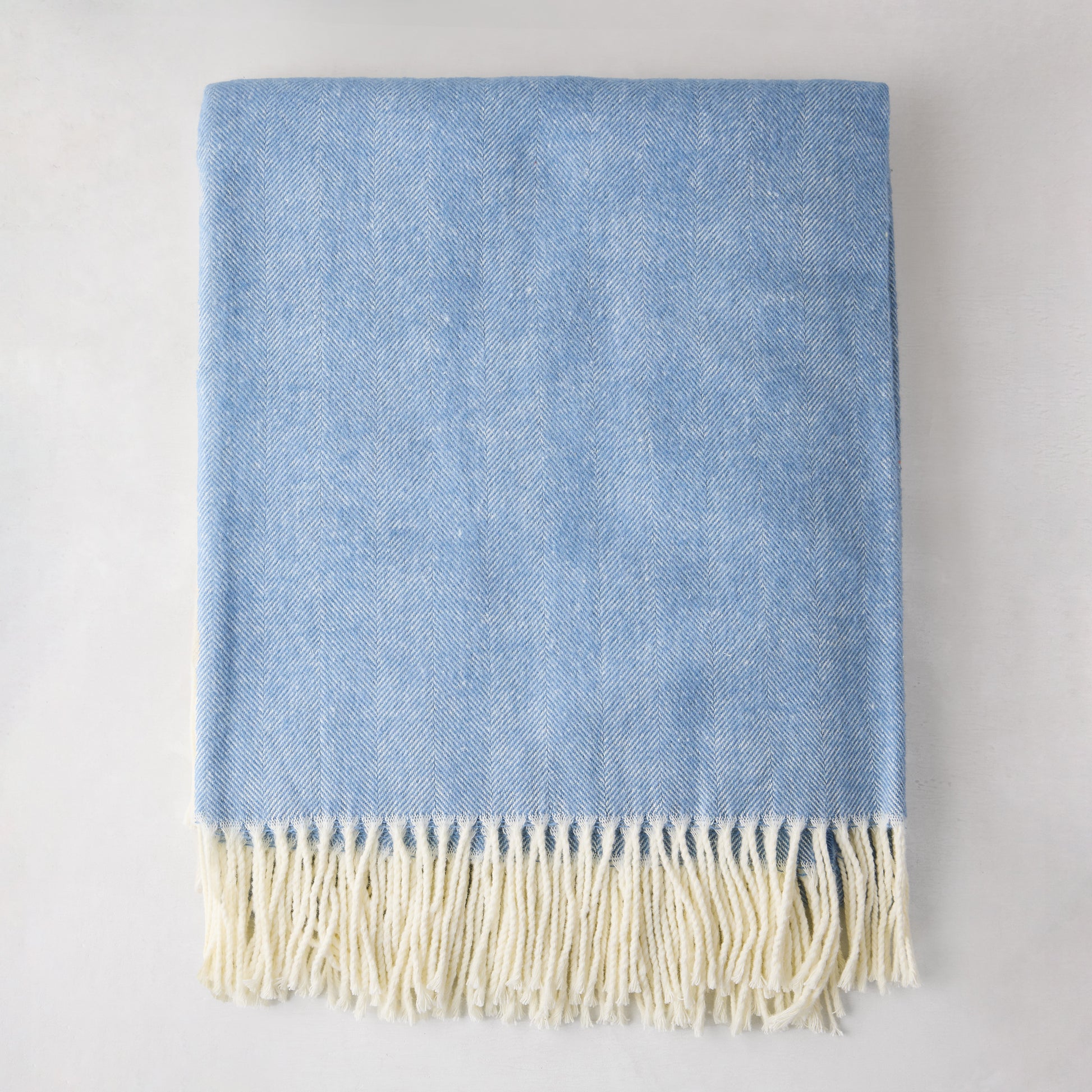 Chambray blue Italian herringbone throw blanket with cream fringe, 51"W x 67"L, 50% cotton, 50% acrylic.