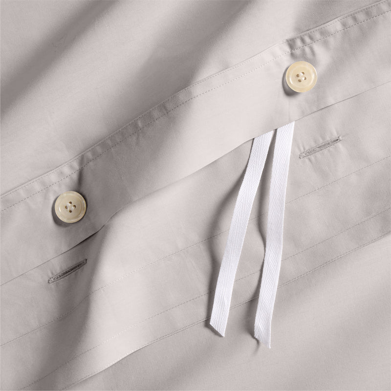 Close-up of charcoal grey Italian percale duvet cover with light buttons and white ties.