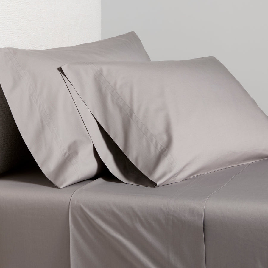 Charcoal Grey Italian Percale Sheet Set with two pillowcases on a bed.