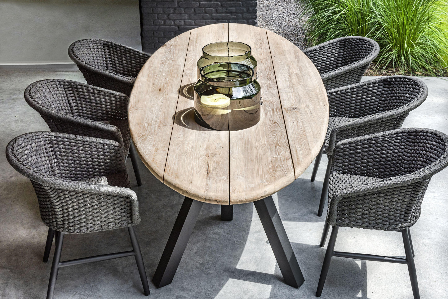 Charly Black Rope Dining Arm Chair with woven PE resin wicker and matte black aluminum frame, around a wood table.