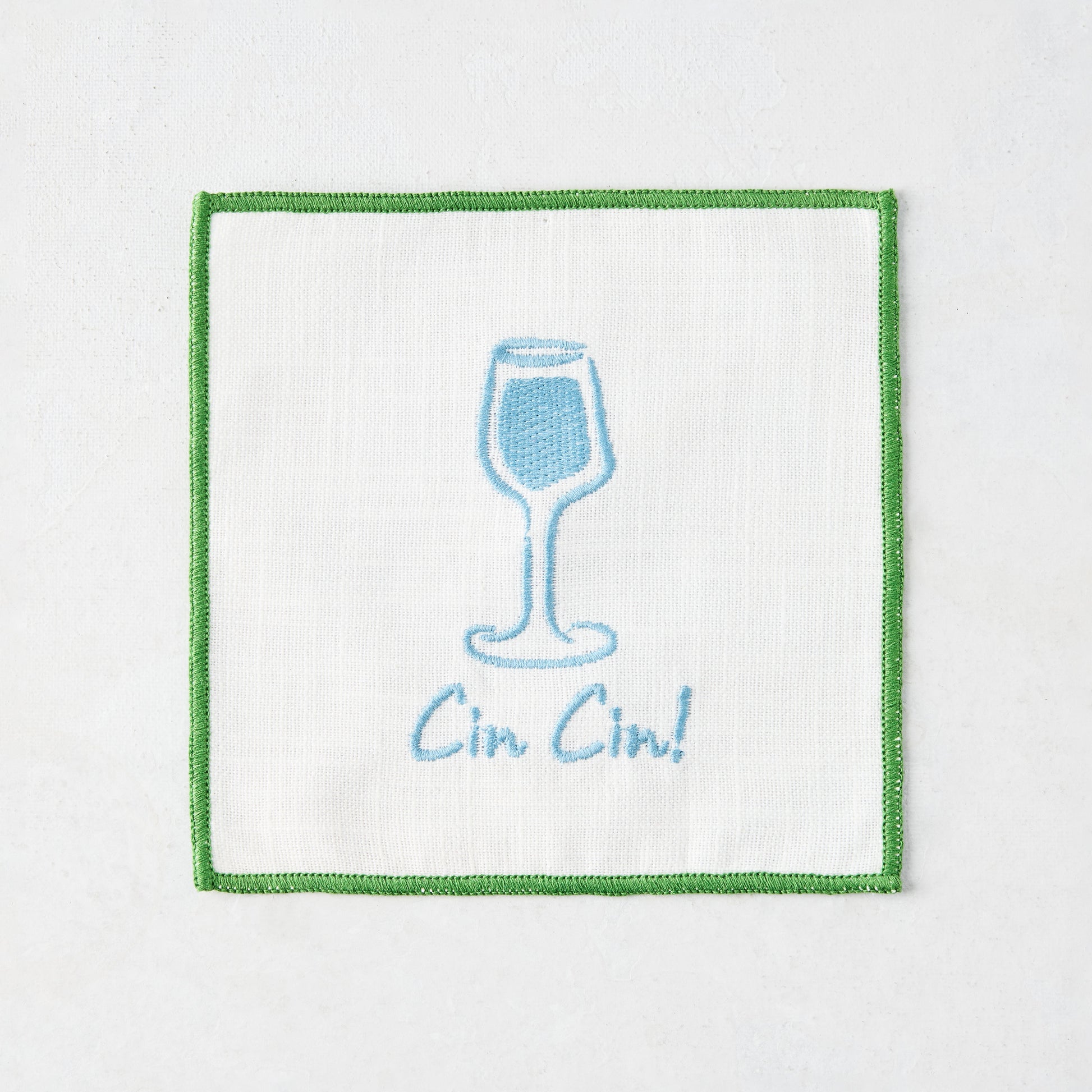 White cotton coaster with blue embroidered cocktail glass and "Cin Cin!" text, green border.