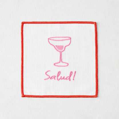 White cotton coaster with red trim, pink embroidered cocktail glass, and "Salud!" text.
