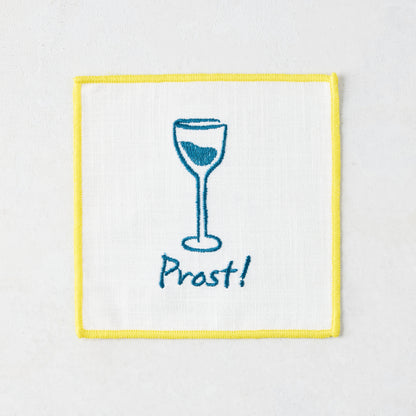 White cotton coaster with yellow trim, blue embroidered wine glass, and "Prost!" text.