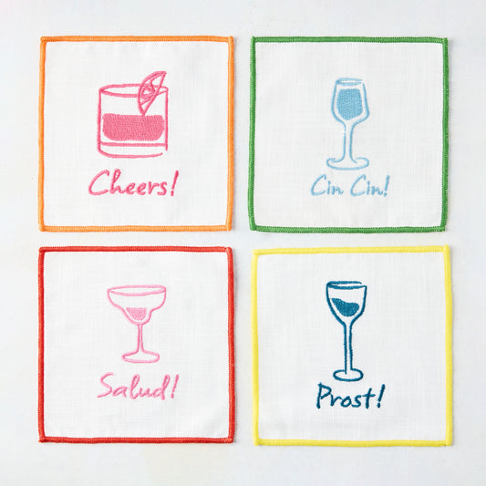 Set of 4 white cotton "Cheers" embroidered coasters with colorful cocktail designs and greetings.