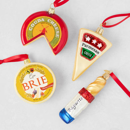 Glass cheese and baguette Christmas ornaments including Gouda, Brie, Parmesan, and bread with red hanging ribbons.