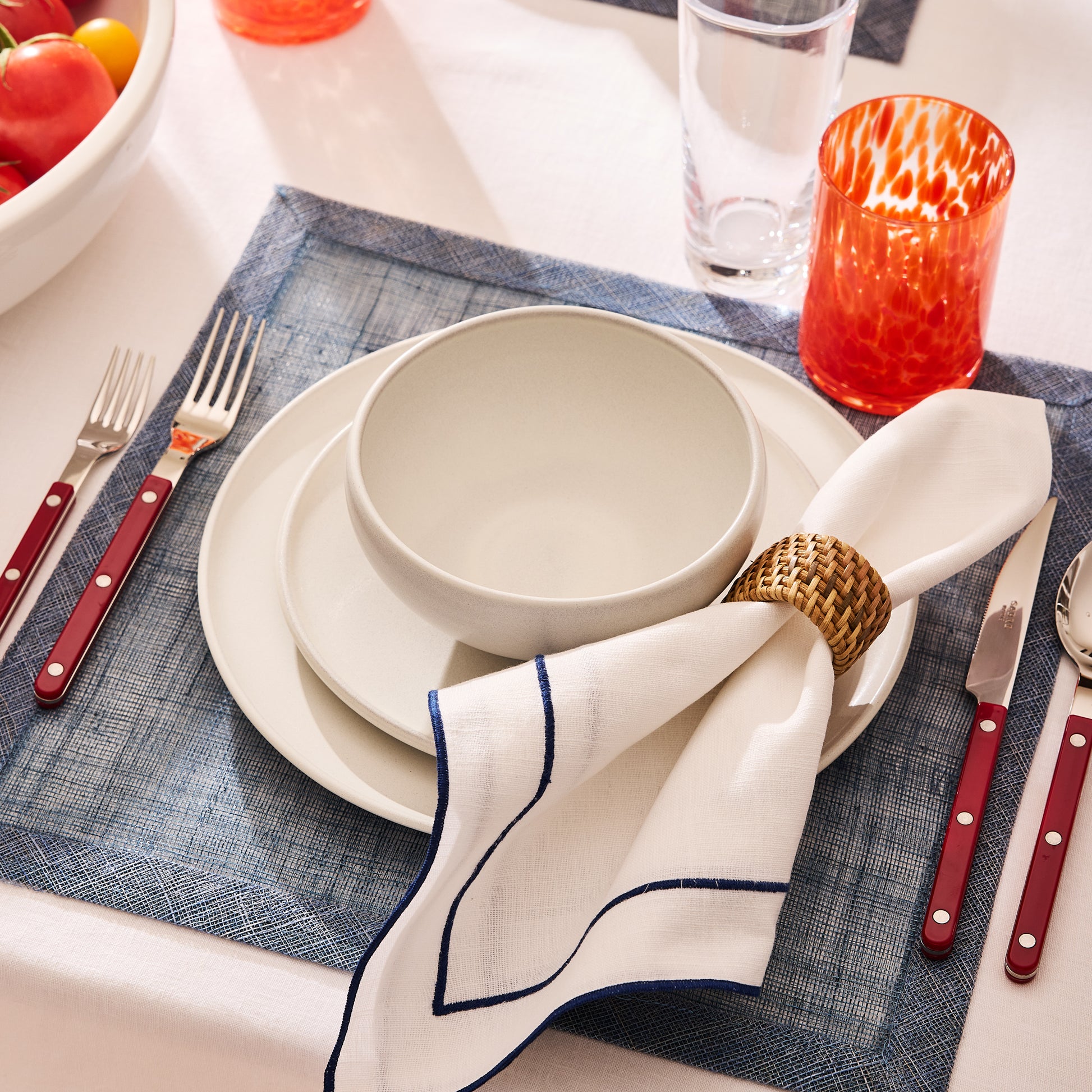 Cherry red Bistro 5-piece flatware set with stainless steel and acrylic handles on a blue placemat.