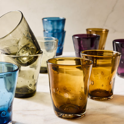 Collection of mouth-blown Henri glasses in chocolate brown, olive, blue, purple, and amber with air bubbles.