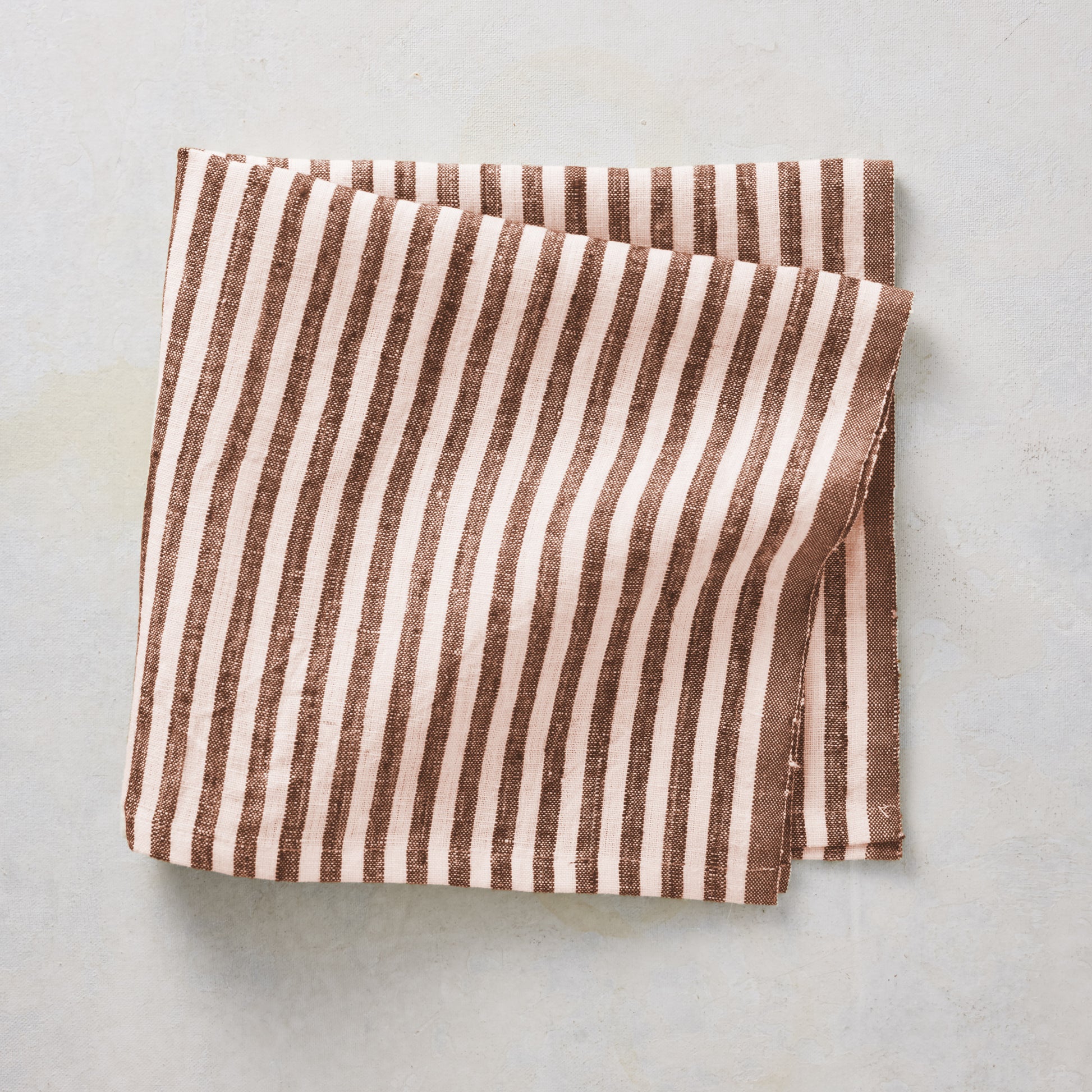 21-inch square linen napkin with chocolate brown ticking stripes on a white base and a brown border.