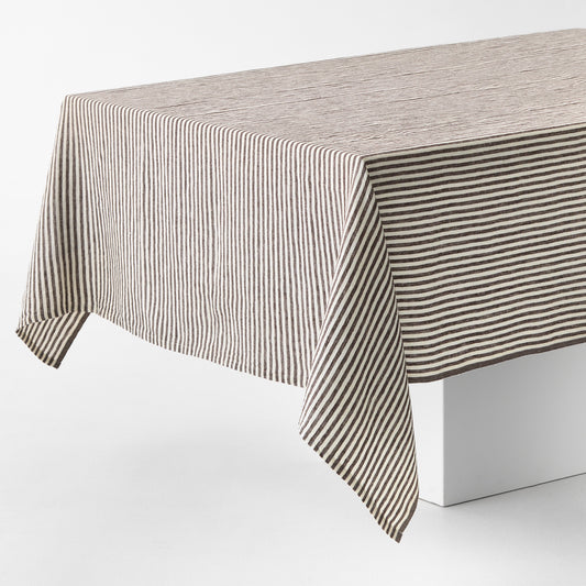 Chocolate brown and white ticking stripe linen tablecloth with a brown border on a white table.
