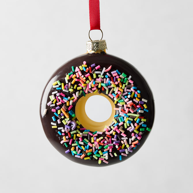 Chocolate donut glass ornament with colorful sprinkles and red ribbon.