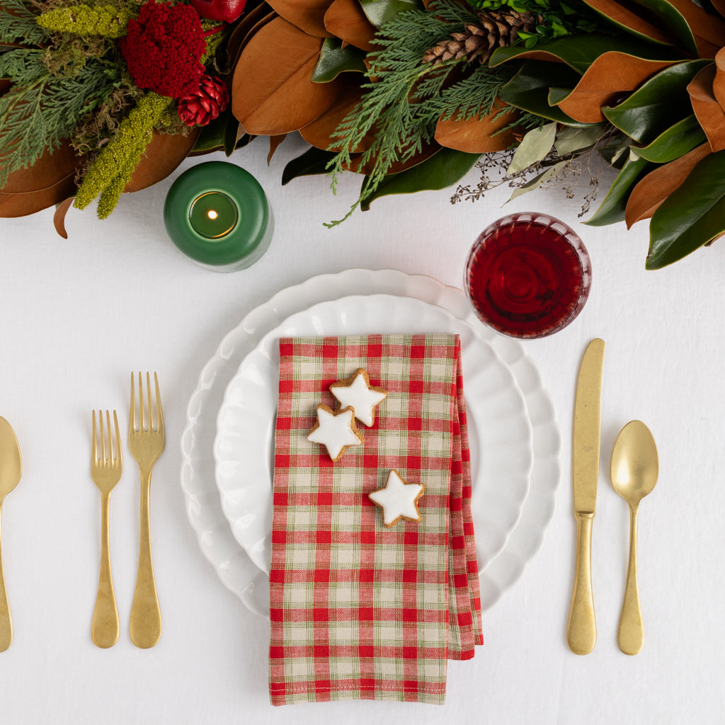 Christmas Cabin Plaid red and beige linen napkin, 21" square, on a white plate with gold flatware.