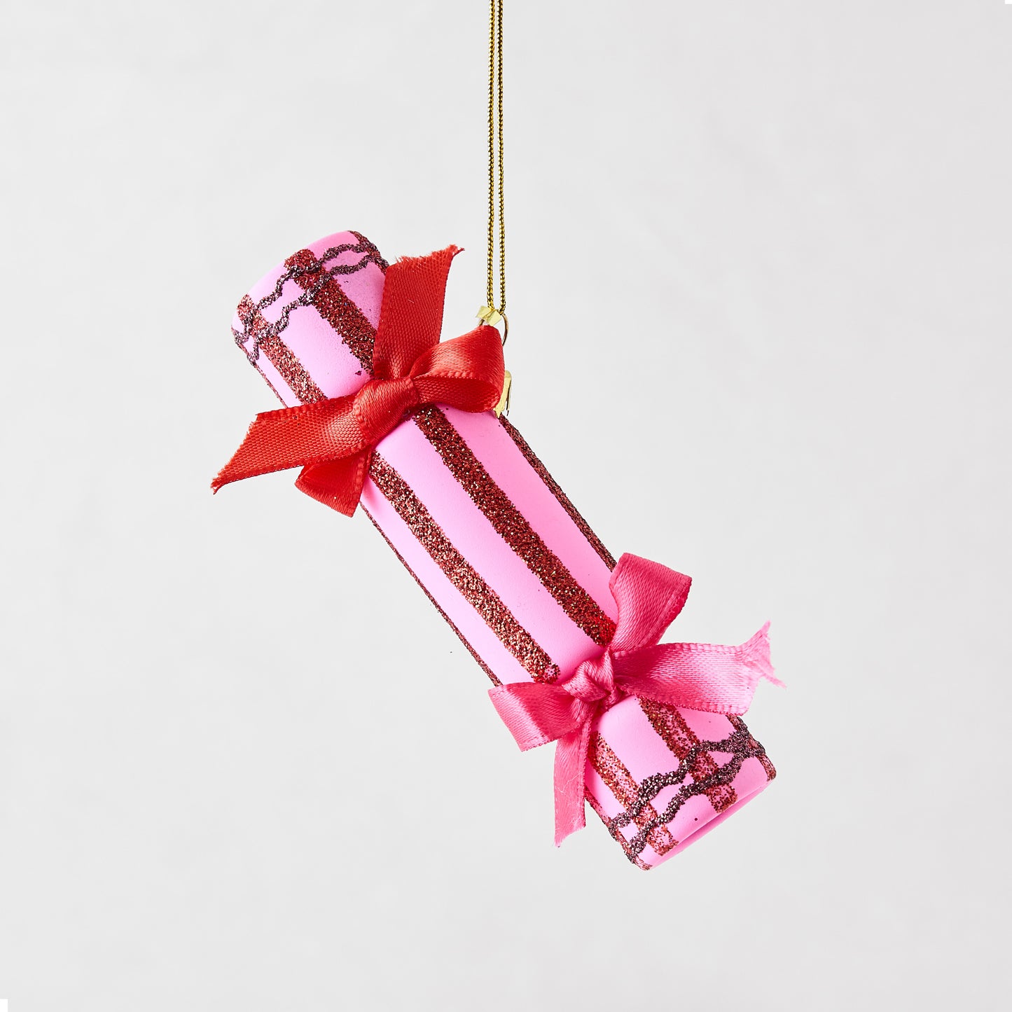 Pink Christmas cracker ornament with red glitter stripes, red and pink satin bows, and a gold hanging cord.