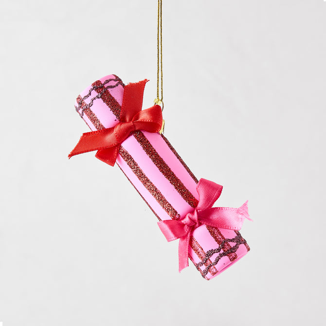 Pink Christmas cracker ornament with red glitter stripes, red and pink satin bows, and a gold hanging cord.