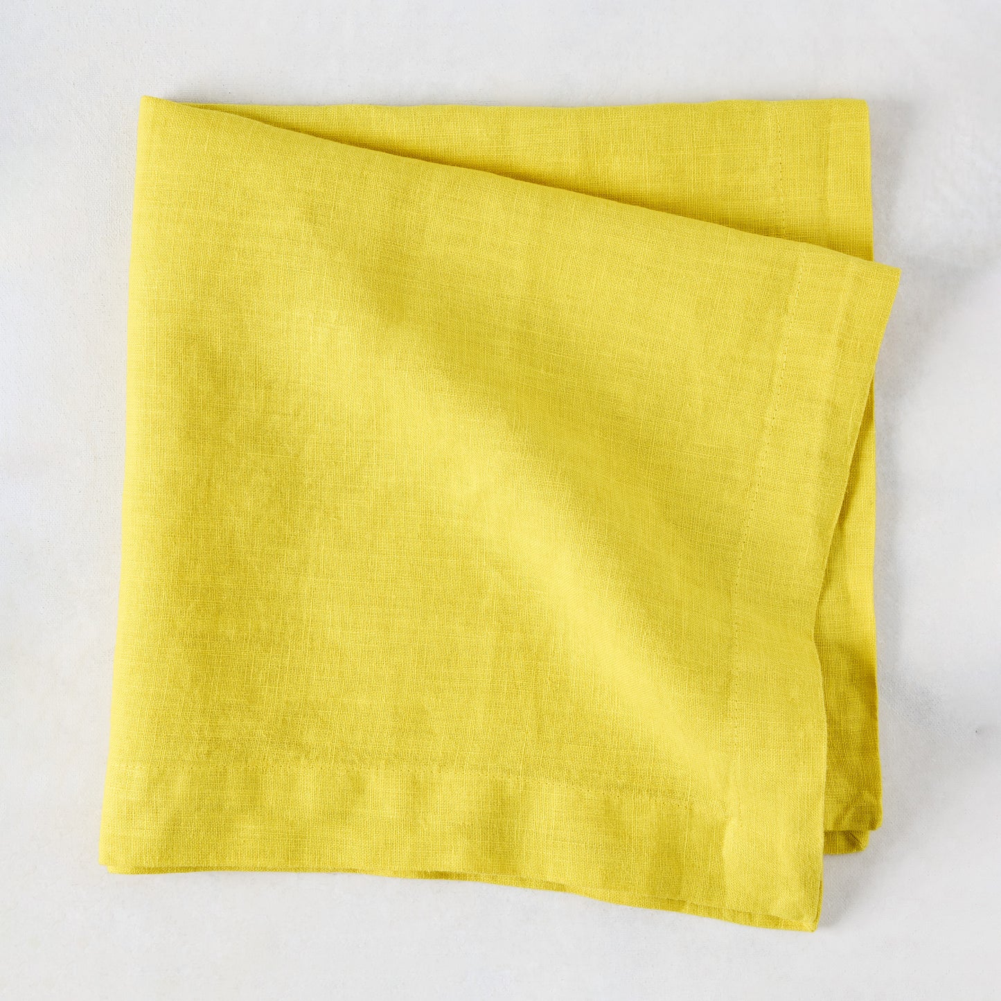 Citron HG Signature hand-dyed, folded lemon yellow linen napkin, 22-inch square.