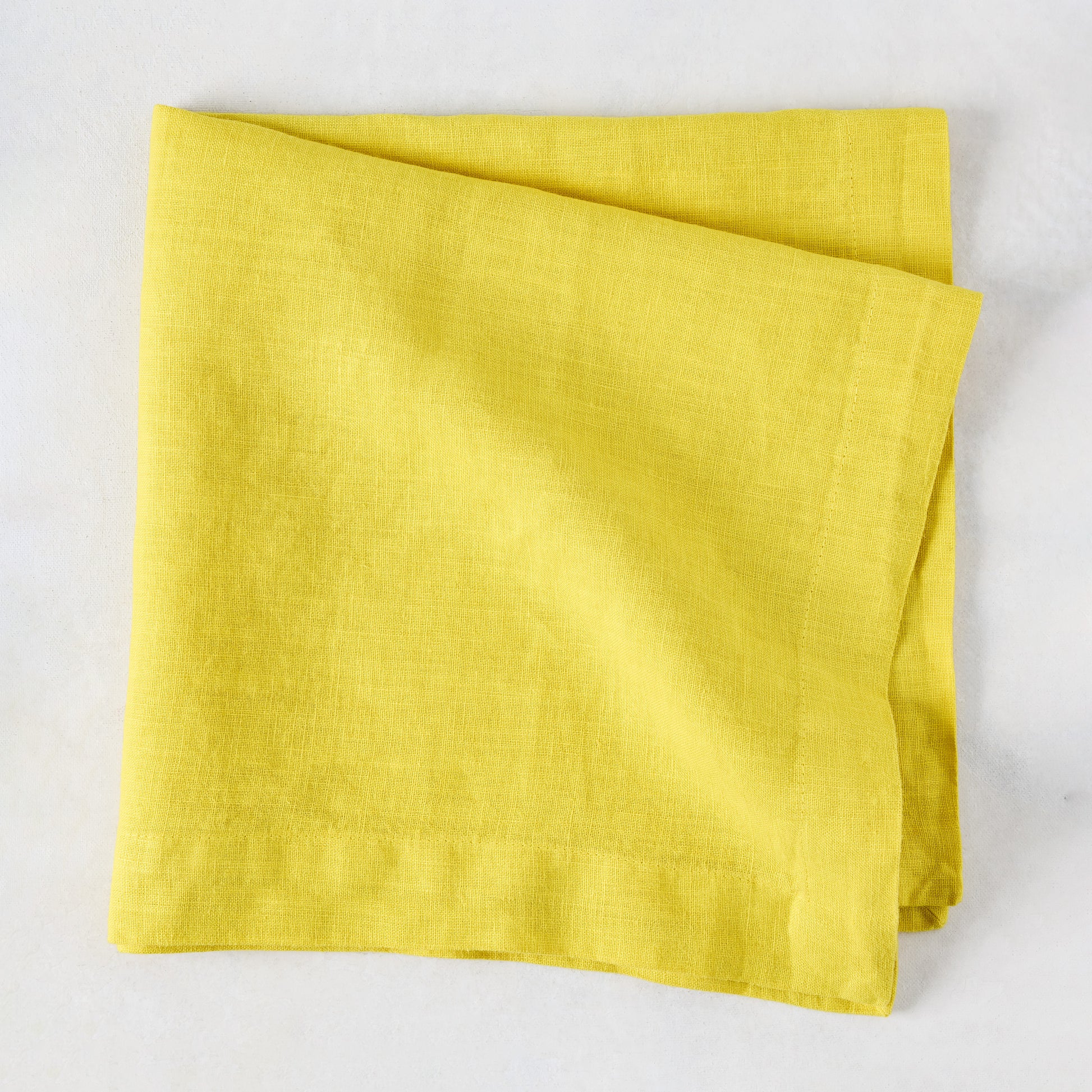 Citron HG Signature hand-dyed, folded lemon yellow linen napkin, 22-inch square.