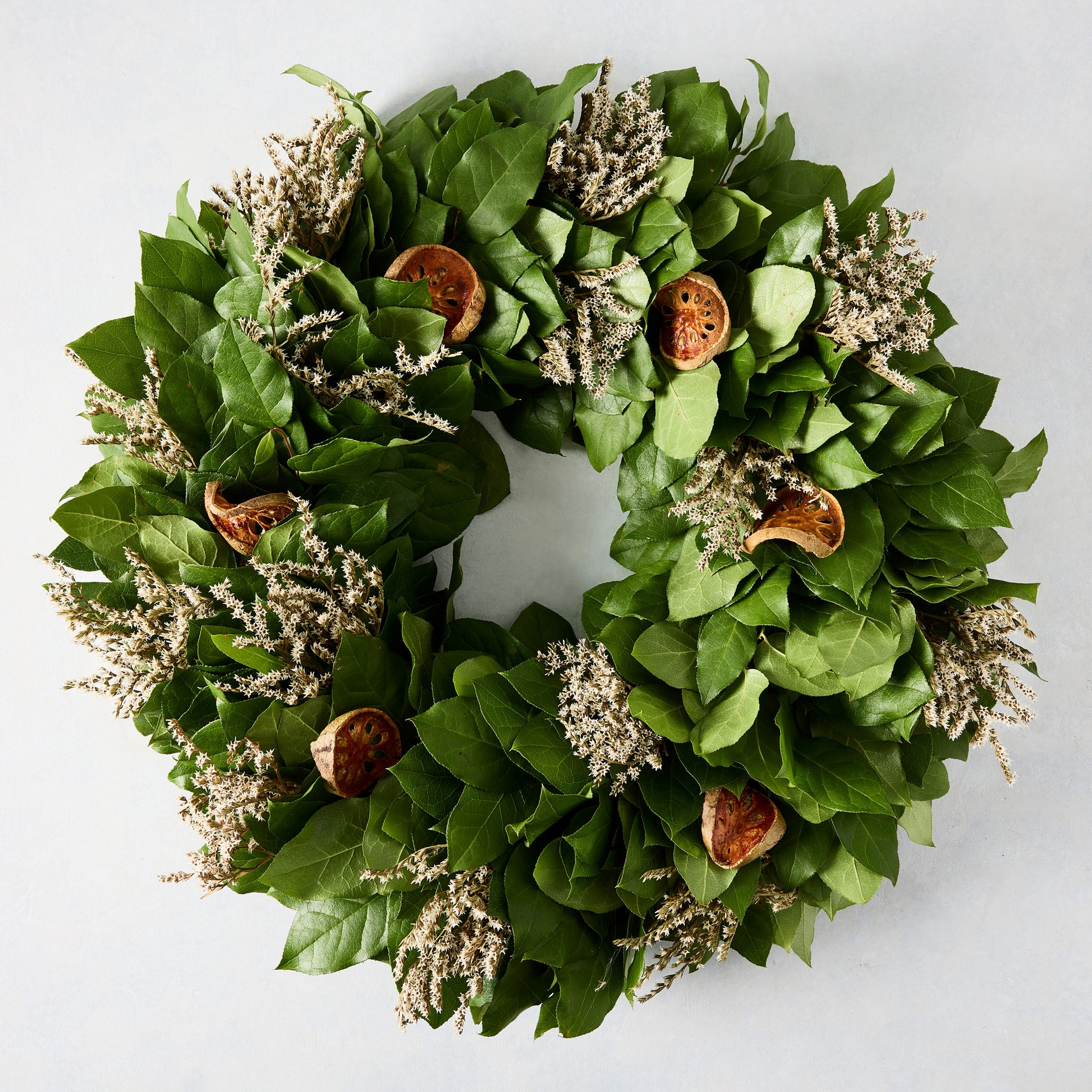 Green privet leaf wreath with dried orange slices and light-colored sprigs.