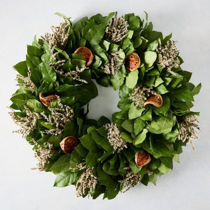 Green privet leaf wreath with dried orange slices and light-colored sprigs.