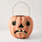 Handcrafted, distressed orange papier-mâché Jack O' Lantern candy bucket with a sad face and black wire handle.