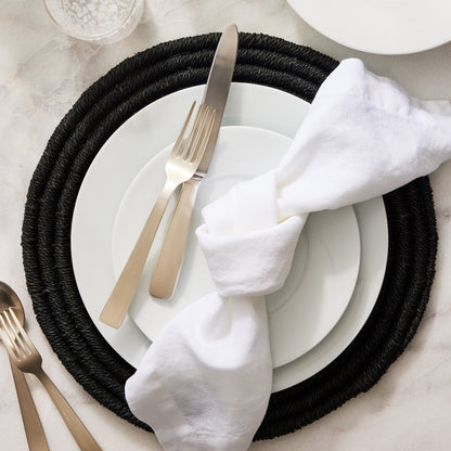 White HG Classic Porcelain Dinner Plate on a black woven placemat with silverware and a white linen napkin.