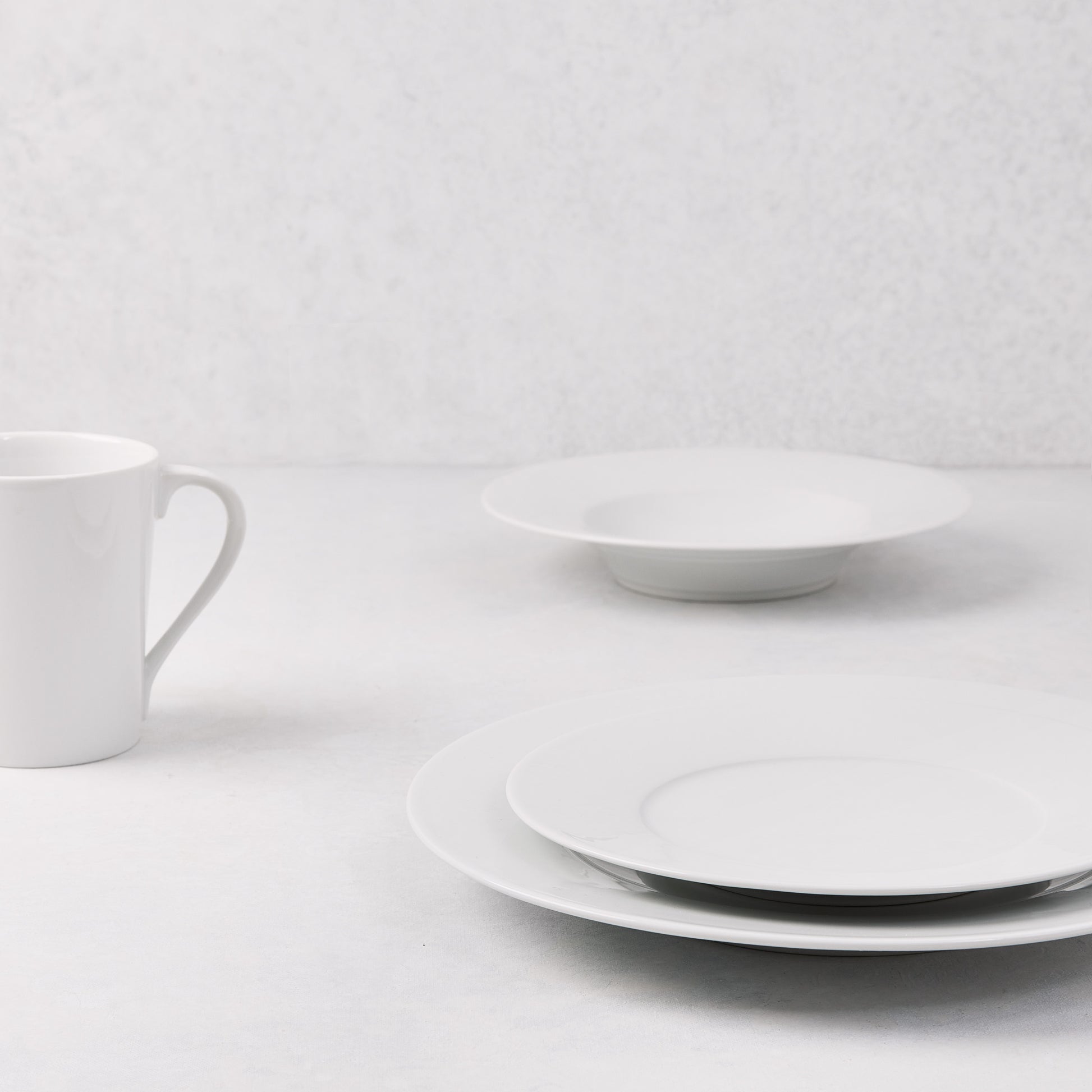 HG Classic white porcelain salad plate, dinner plate, bowl, and mug on a white surface.
