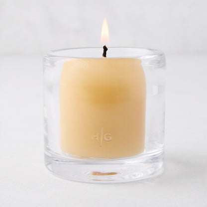 Clear glass votive candle holder with a lit amber votive candle, 2.75"Dia x 2.75"H.