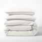 Stack of cloud white European washed linen duvet cover and two matching pillow shams on a white background.