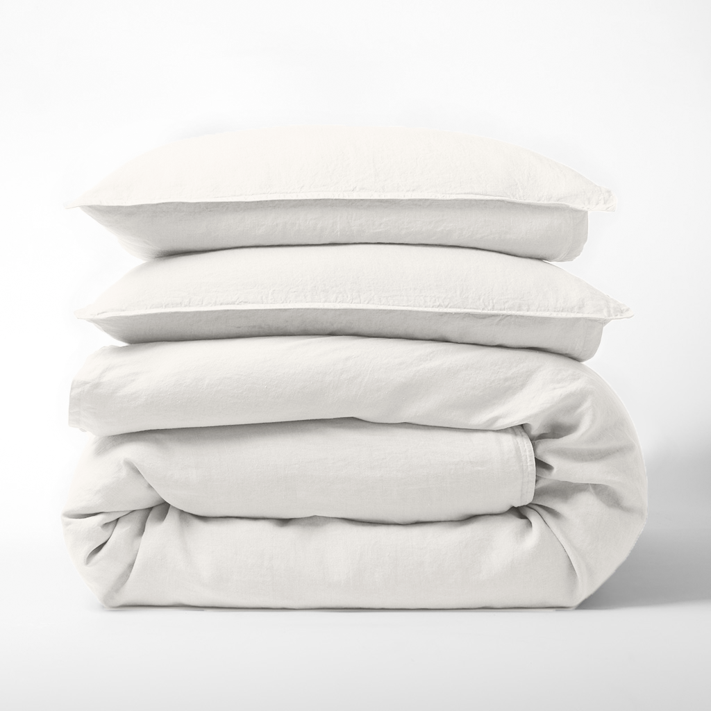 Stack of cloud white European washed linen duvet cover and two matching pillow shams on a white background.