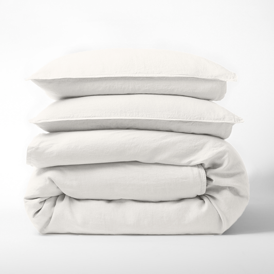 Stack of cloud white European washed linen duvet cover and two matching pillow shams on a white background.