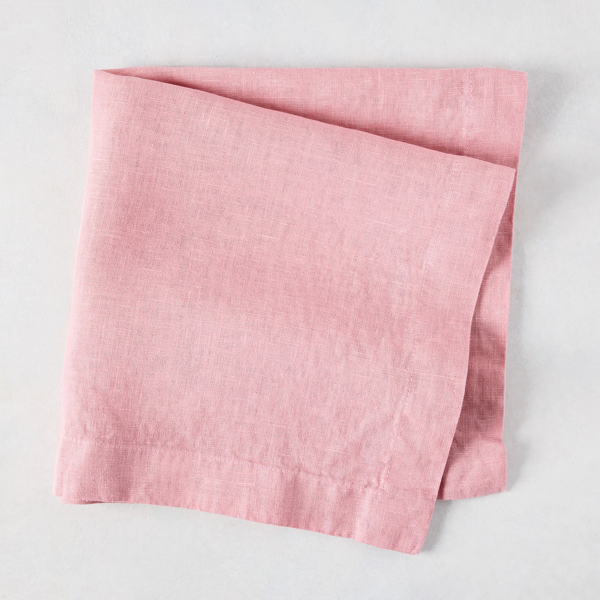 Clover Pink HG Signature hand-dyed linen napkin, 22-inch square, folded on a light surface.