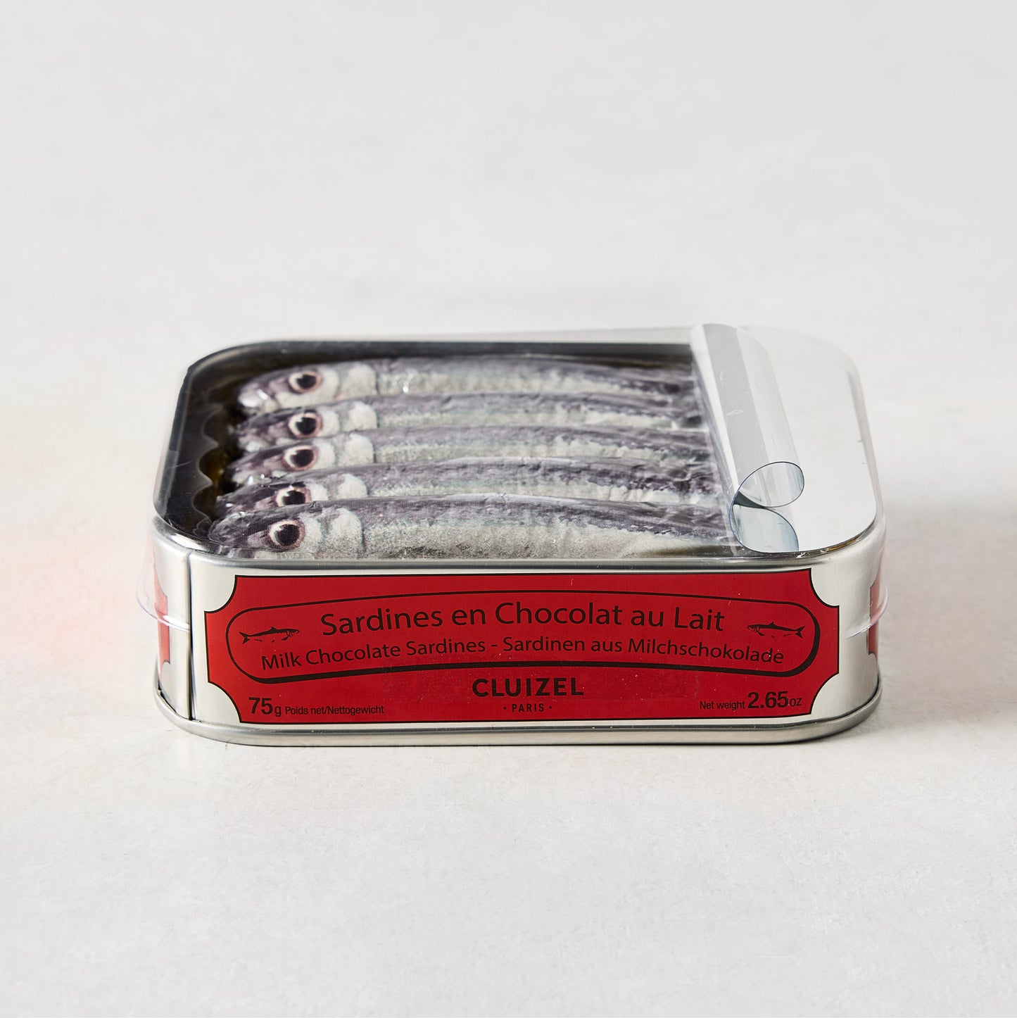 Cluizel Milk Chocolate Tinned Sardines in a silver tin with a red label, showing five chocolate sardines.