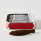 Cluizel Milk Chocolate Tinned Sardines, a silver tin with red label, open to show 5 chocolate sardines, plus one loose.
