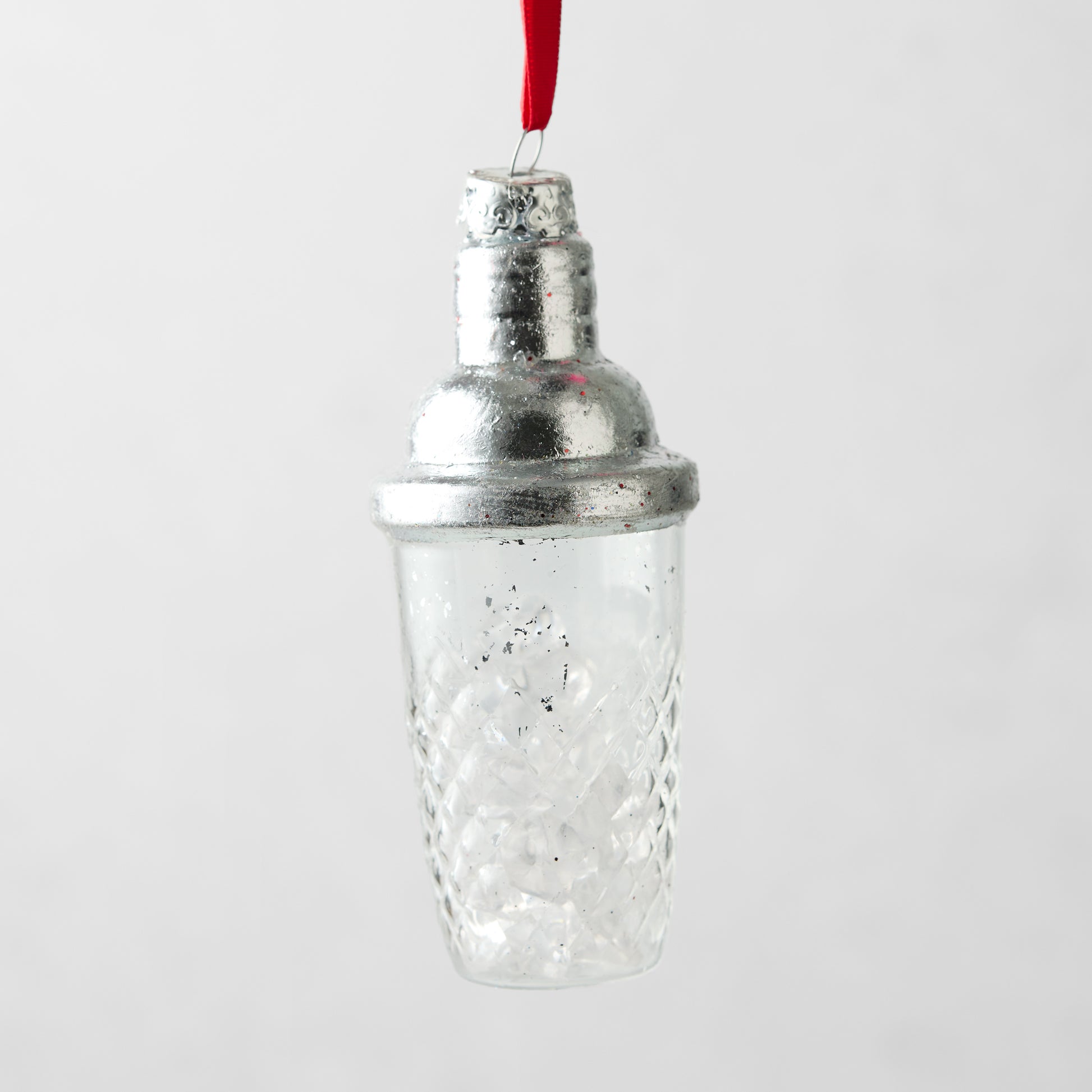 Silver and clear glass cocktail shaker Christmas ornament with a textured diamond pattern and red hanging ribbon.