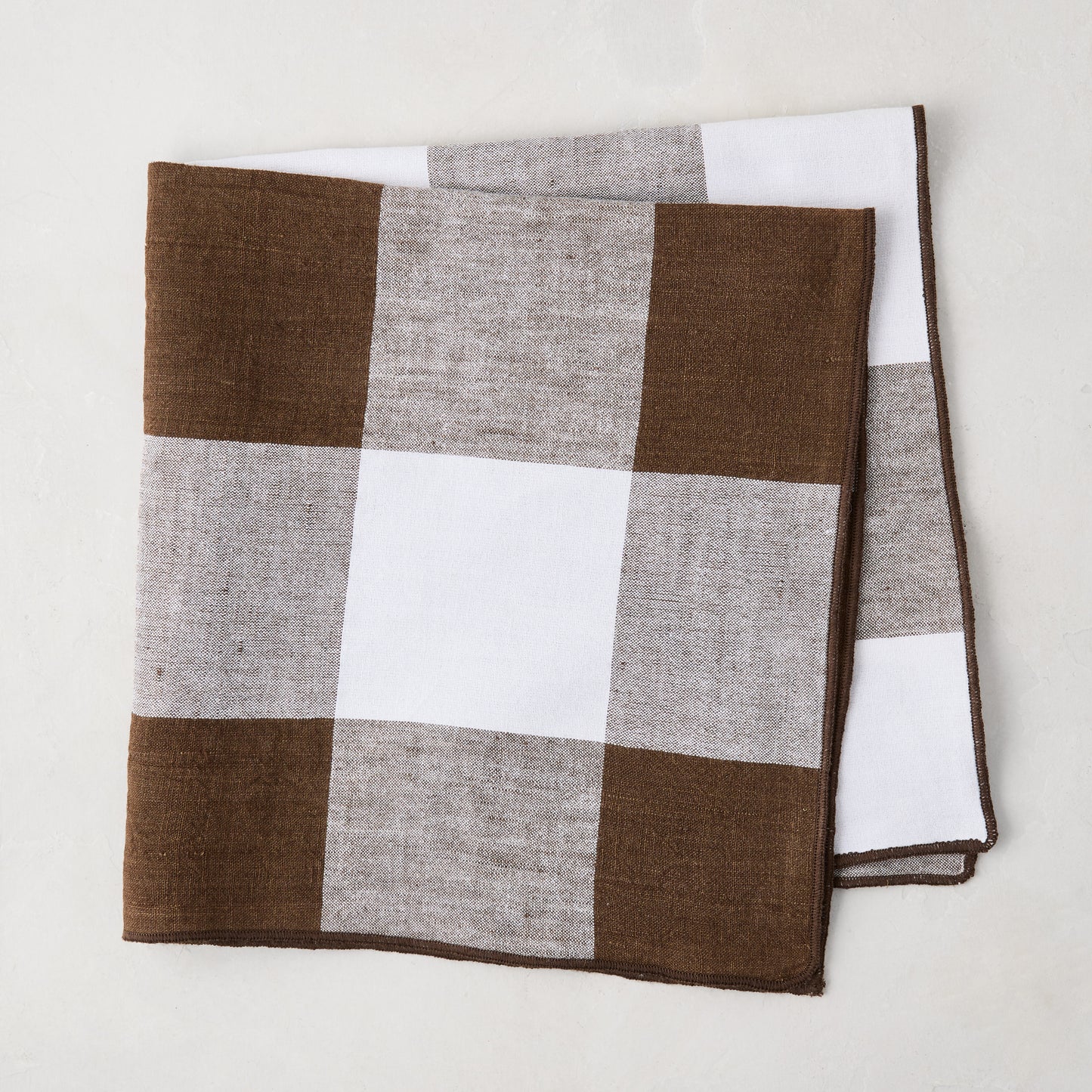 Cocoa brown buffalo check linen napkin, 20x20 inches, folded on a white surface.