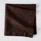 Cocoa HG hand-dyed 22" square brown linen napkin, folded on a light surface.
