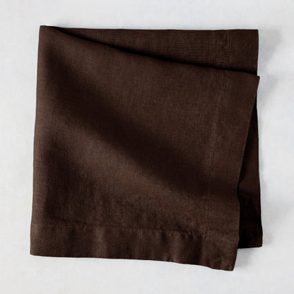 Cocoa HG hand-dyed 22" square brown linen napkin, folded on a light surface.