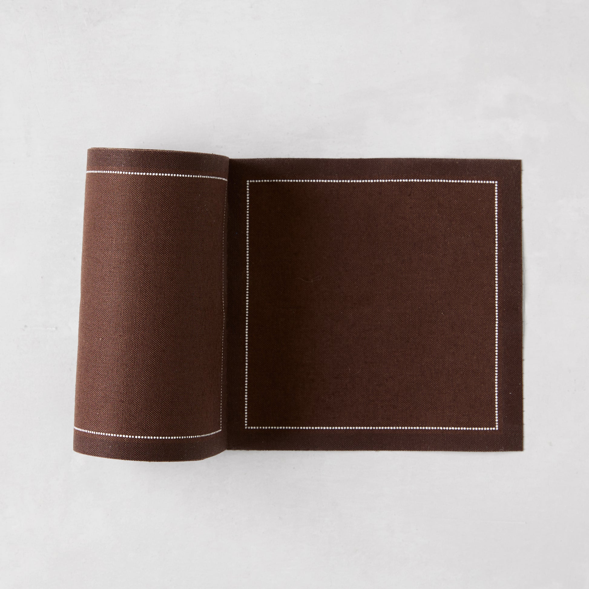 Cocoa brown cotton tear-off cocktail napkin roll with white dotted border.