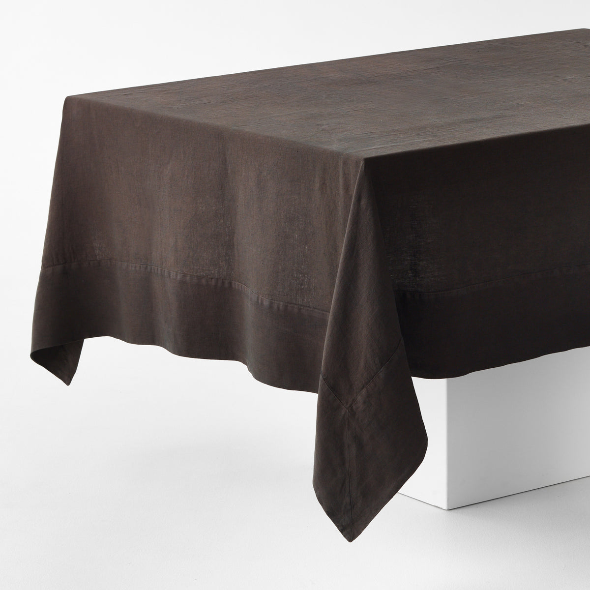 Cocoa brown hand-dyed linen tablecloth with a wide border and mitered corner detailing on a white table.
