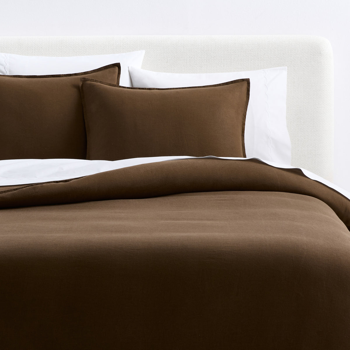 Coffee brown European washed linen duvet cover and matching shams on a bed with white pillows.