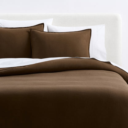 Coffee brown European washed linen duvet cover and matching shams on a bed with white pillows.