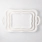 Colette white ceramic serving platters, set of 3, with scalloped edges and handles, stacked.