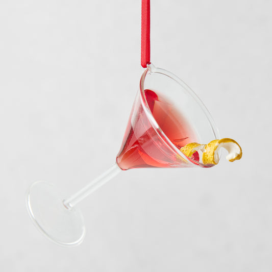 Handmade glass Cosmopolitan Christmas tree ornament with red liquid, lemon twist, and red ribbon.