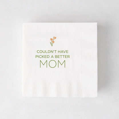White paper cocktail napkin with "Couldn't Have Picked a Better Mom" in green, topped with orange tulips.