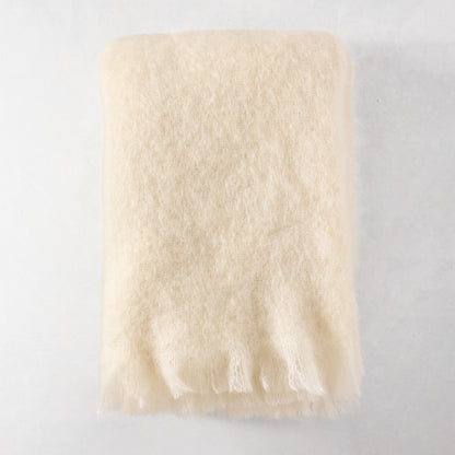 Folded cream mohair throw blanket with fringe, 72"L x 51"W.