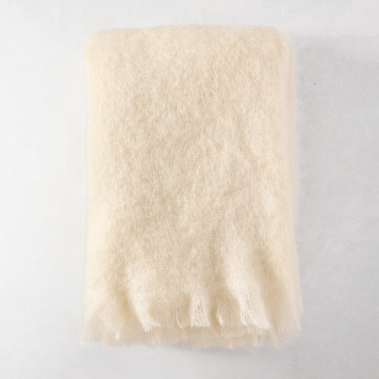 Folded cream mohair throw blanket with fringe, 72"L x 51"W.