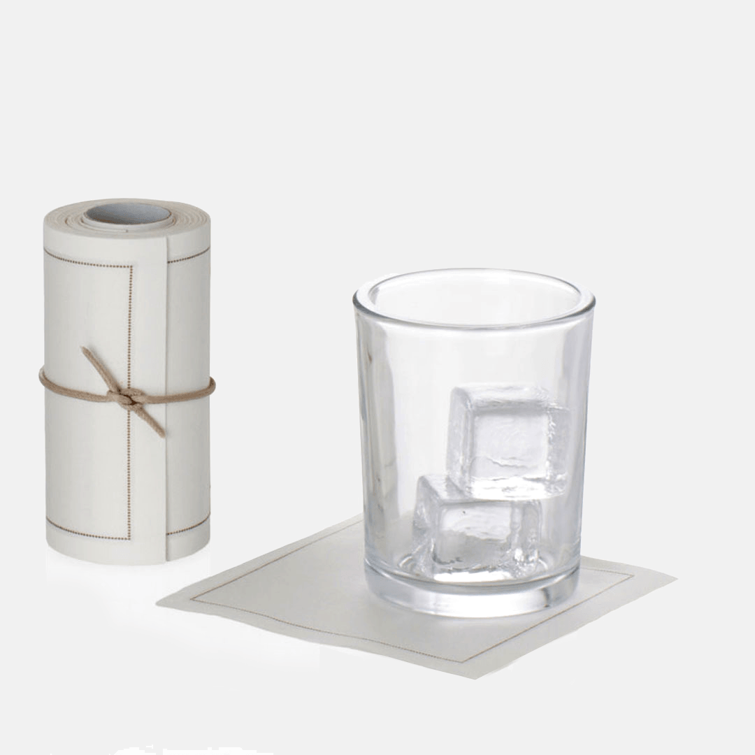 Roll of 50 cream cotton tear-off cocktail napkins with a glass of ice on one napkin.